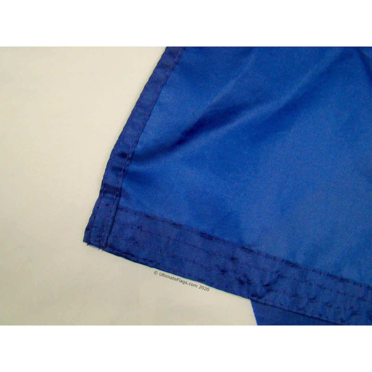 This image showcases a close-up of a blue flag's hem, highlighting its durable stitching and quality finish. Ideal for those looking to buy online, this affordable flag is perfect for various occasions. Discover the best options at UltimateFlags.com.