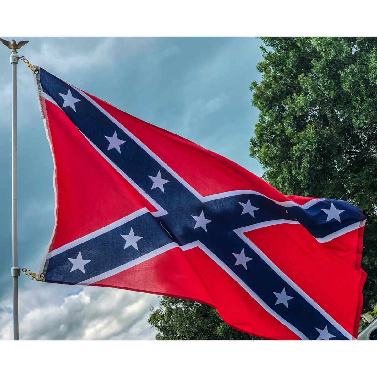 Confederate flag waving in the wind against a cloudy sky, showcasing its vibrant red and blue colors with white stars. For the best deals on affordable flags, including this one, buy online at UltimateFlags.com.
