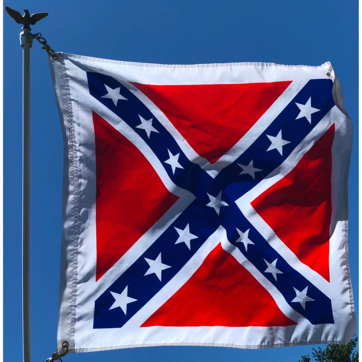 Confederate flag waving against a clear blue sky, showcasing its vibrant colors and distinct design. Perfect for collectors and enthusiasts looking for cheap and affordable options. Buy online for the best deals at UltimateFlags.com.