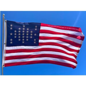 American flag waving against a clear blue sky, representing patriotism and national pride. Ideal for those searching for a cheap and affordable flag option. Buy online for the best deals at UltimateFlags.com.