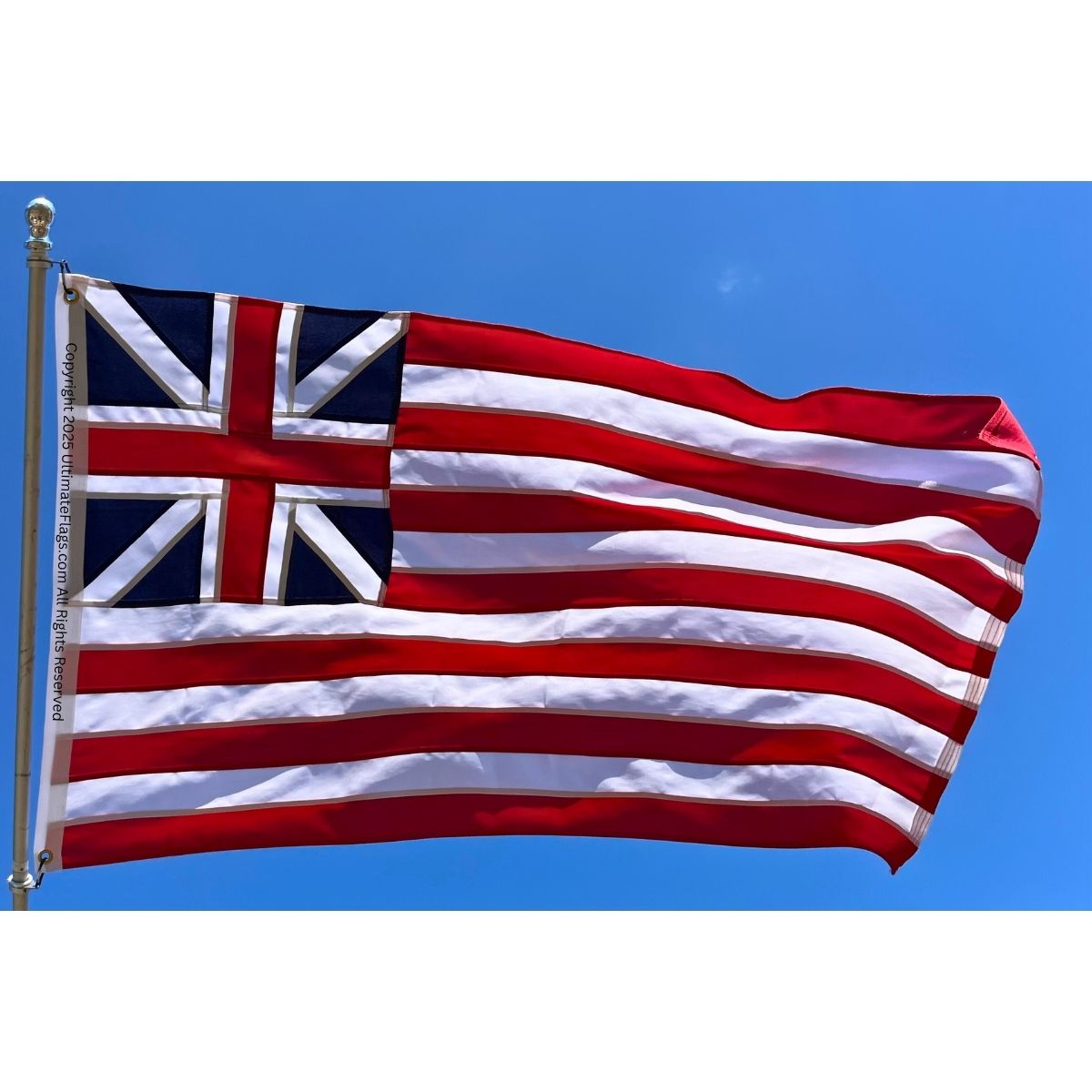 British flag waving against a clear blue sky, representing national pride and heritage. Find the best deals on affordable flags to buy online at UltimateFlags.com.
