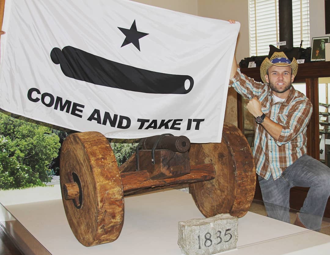 Historical display featuring a vintage cannon with the "Come and Take It" flag, representing Texas pride and independence. This unique piece is perfect for collectors and history enthusiasts looking for cheap and affordable decor options. Buy online for the best selection at UltimateFlags.com.