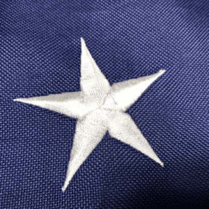 This image features a close-up of a five-pointed star on a blue background, showcasing high-quality craftsmanship. Discover cheap and affordable flags with the best designs to buy online at UltimateFlags.com.