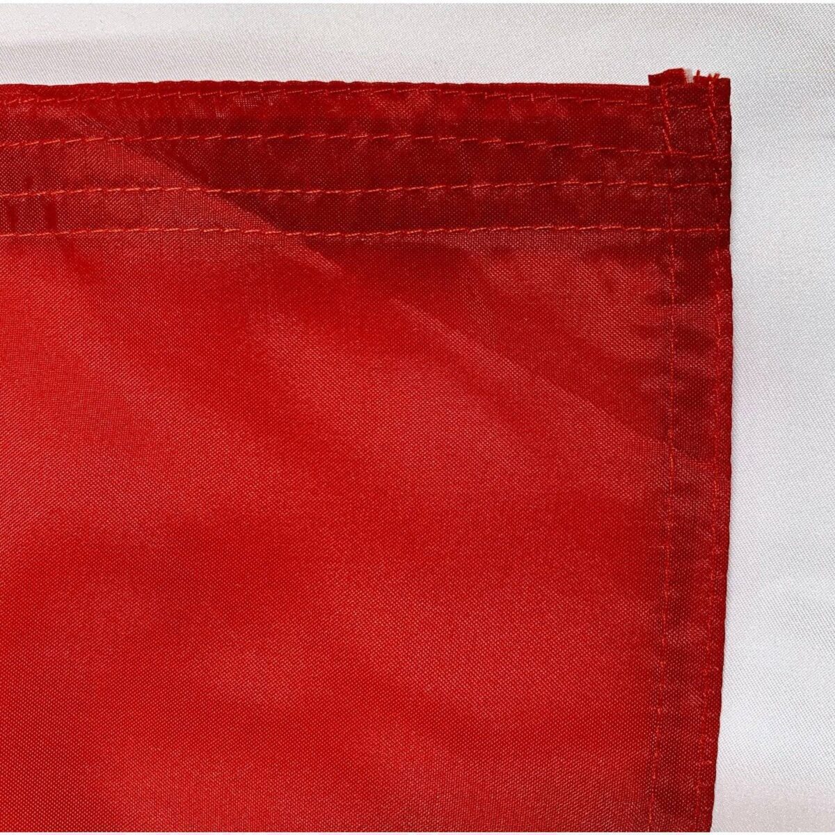 Durable red flag corner detail, perfect for outdoor use and available in various sizes. Ideal for those looking to buy online at affordable prices. Get the best deals on flags at UltimateFlags.com.
